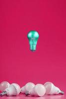 A special Light bulb hovers over simple, standard white light bulbs on a pink background.