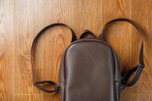 Backpack made of brown genuine leather on a wooden background. photo