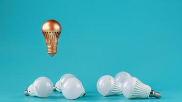 A prominent gold light bulb levitates above an environment of white led bulbs. photo