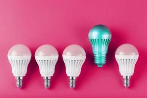 A special Light bulb stands out from the group of ordinary white light bulbs on a pink background. photo