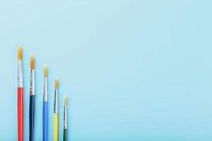 Multi-colored paint Brushes on a blue background. photo