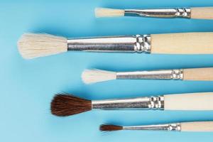 Brushes for drawing made of natural wood and wool. on a blue background. photo