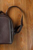 mochila hecha de cuero genuino marrón sobre un fondo de madera. foto