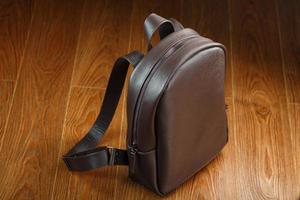 Leather backpack or satchel made of brown leather on a wooden background. photo