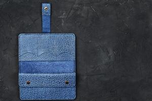billetera de cuero azul sobre un fondo texturizado negro. foto