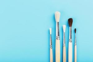 Brushes for drawing with paints made of natural wood and wool on a blue background. photo