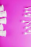 Disposable white plastic tableware on a pink background. photo