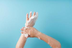 Children's hands in soap suds, on a blue background, top view. photo