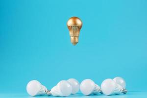 A prominent gold light bulb levitates above an environment of white led bulbs. photo