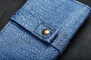 billetera de cuero azul sobre un fondo texturizado negro. foto