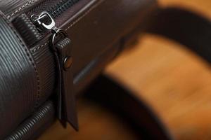 Close-up elements and details of the Backpack made of brown genuine leather on a wooden background. photo