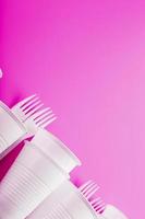 Disposable white plastic tableware on a pink background. photo