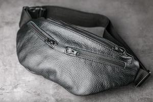 Belt bag made of textured black leather, banana on a gray background. photo