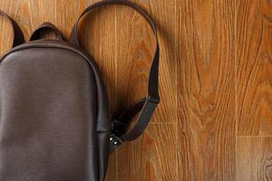 Backpack made of brown genuine leather on a wooden background. photo