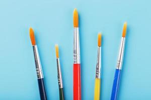 Multi-colored brushes for drawing and art on a blue background. photo