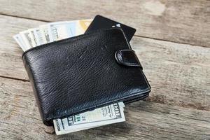 billetera negra con billetes, tarjetas electrónicas y bitcoins sobre un fondo de madera. símbolo de prosperidad y prosperidad. foto