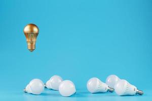 The Golden light bulb rises and hovers above the surroundings of ordinary light bulbs. photo