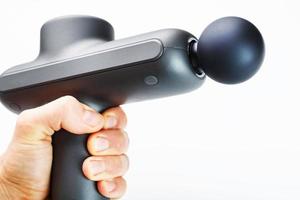 Manual electric body massager in hand on a white background.