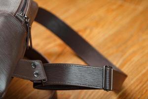 Close-up elements and details of the Backpack made of brown genuine leather on a wooden background. photo