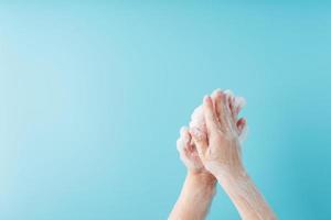 Hands of a child in soapy antibacterial foam, on a blue background, top view. photo