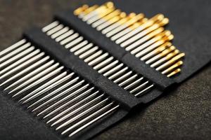 Gold sewing needles on a black background in a row. photo