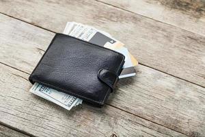 Black wallet with banknotes, electronic cards and bitcoins on a wooden background. Symbol of prosperity and prosperity. photo