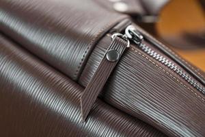 Close-up elements and details of the Backpack made of brown genuine leather on a wooden background. photo