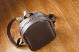 Close-up elements and details of the Backpack made of brown genuine leather on a wooden background. photo