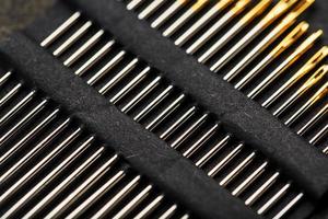 Set of Gold needles on a black background in a row. photo