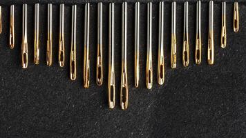 Set of Gold needles on a black background in a row. photo