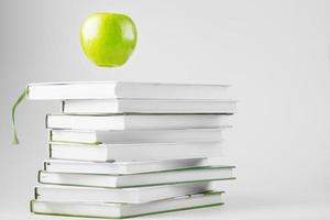 A green Apple hovers over isolate books on a white background. photo