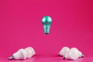 A special Light bulb hovers over simple, standard white light bulbs on a pink background. photo