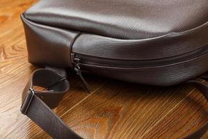 Close-up elements and details of the Backpack made of brown genuine leather on a wooden background. photo