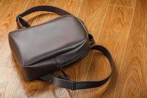mochila de cuero o bolso de cuero marrón sobre un fondo de madera. foto