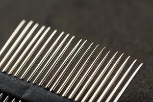 Gold sewing needles on a black background in a row. photo