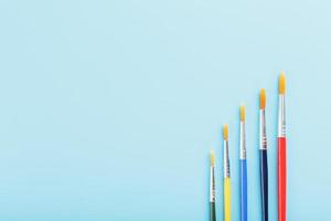 Multi-colored paint Brushes on a blue background. photo