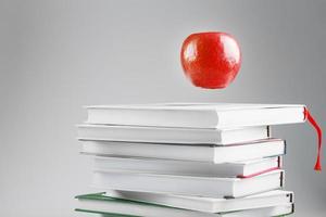 A red Apple hangs above the books on a white background. photo