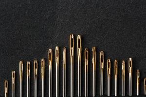 conjunto de agujas de oro sobre un fondo negro en una fila. foto