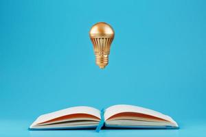 A Golden light bulb in levitation from an open notebook on a blue background. Concept of the idea. photo