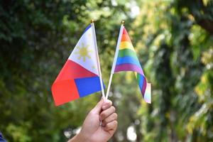 Rainbow flag and Philipines national flag holding in hand, soft and selective focus, concept for celebration of lgbtq in pride month around the world. photo