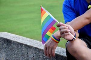 bandera del arco iris y pulseras en las manos, enfoque suave y selectivo, concepto para celebraciones de géneros lgbtq y llamando a todas las personas a respetar los derechos humanos en el mes del orgullo en todo el mundo. foto