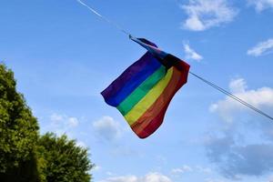 LGBTQ flag is tied on a rope and is being lifted to the top of the pole, concept for lgbtq genders celebrations in pride month around the world and respecting genders diversity of humans. photo