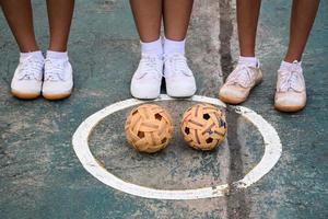 jóvenes jugadoras de sepak takraw del sudeste asiático paradas cerca de las pelotas en el centro de servicio de la cancha, al aire libre sepak takraw jugando después de la escuela, enfoque suave y selectivo. foto