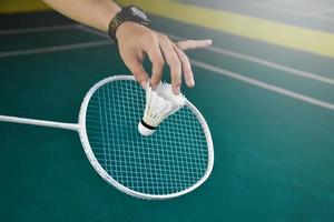 Badminton player holds racket and white cream shuttlecock in front of the net before serving it to another side of the court. photo