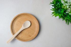 Wooden utensils on the kitchen table. Round wooden plate, a wooden spoon, a green plant. The concept of serving, cooking, cooking, interior details. Top view. photo