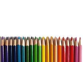 lápices de colores para dibujar dispuestos por el color del arco iris sobre un fondo blanco foto