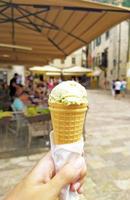 helado en una taza de gofre de cono en una mano en el fondo de la ciudad vieja europea foto