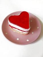 heart-shaped strawberry cake on a pink plate on a white background photo