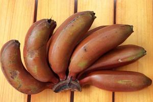 Bunch of reddish banana on close up view on wooden background photo