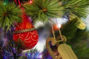 coloridas decoraciones navideñas en un abeto con luces borrosas. foto